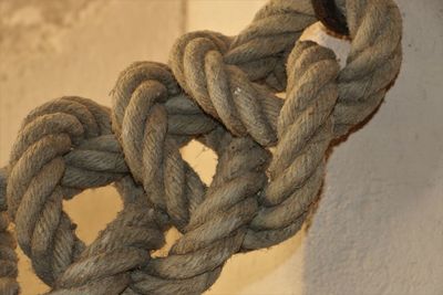 Close-up of rope tied on wood against wall