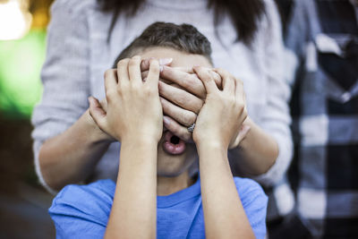 Midsection of mother covering sons eyes outdoors