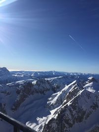 Aerial view of snowcapped mountains against blue sky