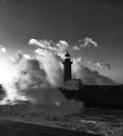 Lighthouse by sea against sky