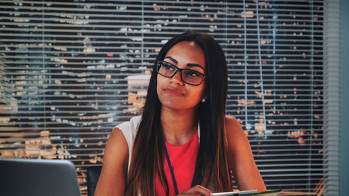 Young woman looking away while sitting at office