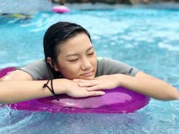 Close-up of teenage girl with inflatable ring swimming in pool