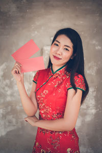 Portrait of a smiling young woman holding red umbrella