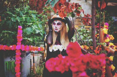 Portrait of young woman standing by flowering plants