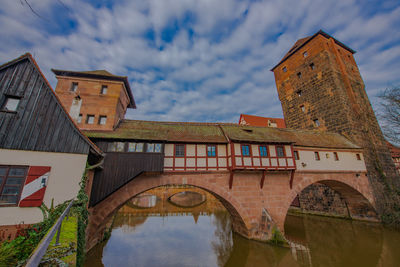 Low angle view of arch bridge by building against sky