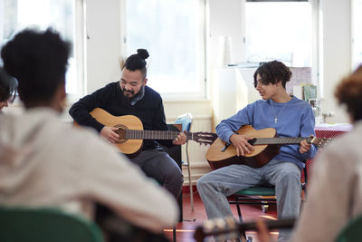 Teenagers attending guitar lesson