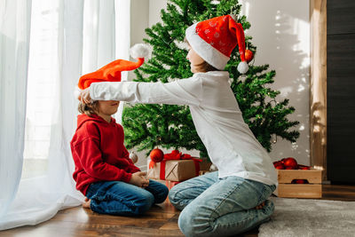 New year's and christmas. a sister helps her little brother put on a christmas santa hat