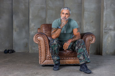 Portrait of senior man sitting against wall