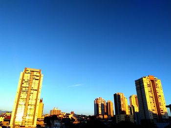 Low angle view of skyscrapers against blue sky