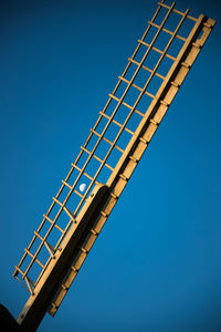 Low angle view of moon through a sail of a windmill against clear blue sky