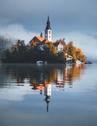 Traditional building by lake against sky