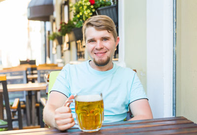 Portrait of smiling man holding beer glass at bar