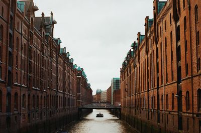 Canal amidst buildings against sky in city