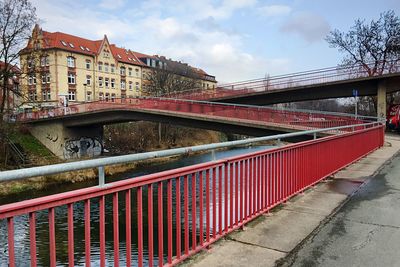 Bridges over river by buildings against sky