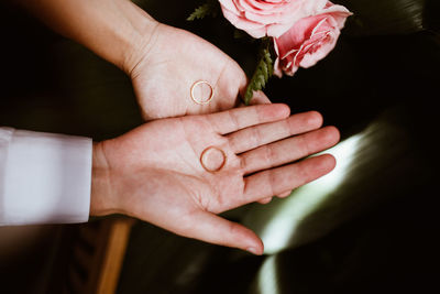 Cropped hands of couple holding wedding rings