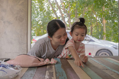 Cute girl looking at while sitting on table