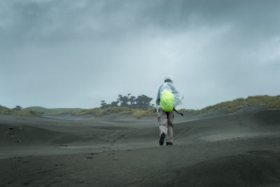 Full length rear view of man walking on desert