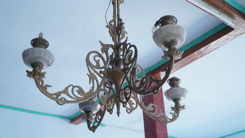 Low angle view of electric lamp hanging against sky