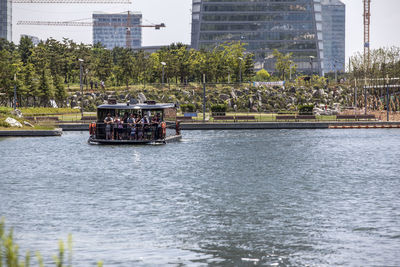 Passengers enjoying in boat over lake against buildings