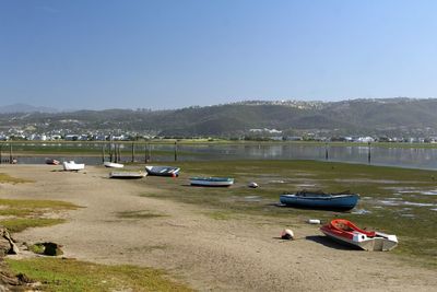 Boats moored on shore against clear sky