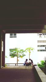 Man sitting on bench against building in city