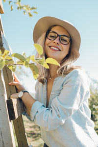 Portrait of smiling young woman standing against sky