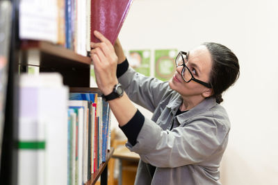 Woman picking book from bookshelf