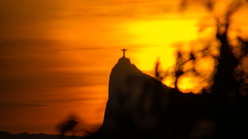 Silhouette of temple against building during sunset