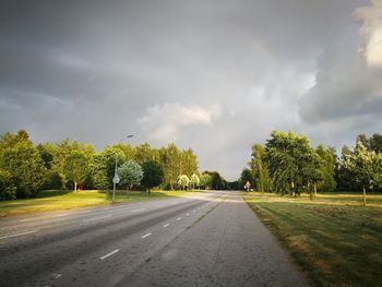 Road amidst trees and plants against sky
