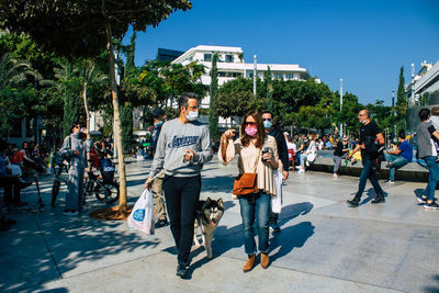 Group of people walking on sidewalk in city