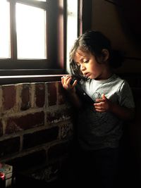 Cute baby boy holding digital tablet by window at home