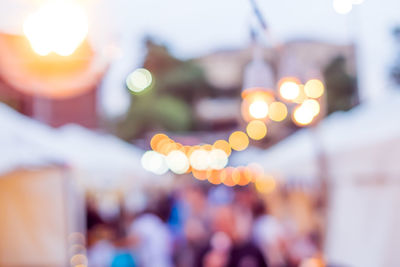 Defocused image of illuminated lights against sky in city