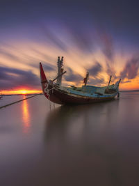 Fishing boat in sea against sky during sunset