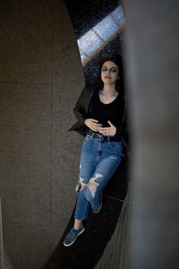 Portrait of young woman standing against wall