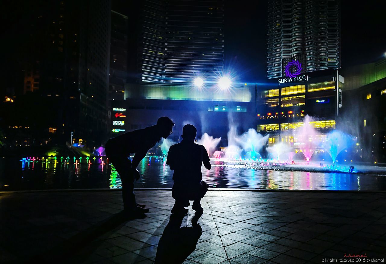 PEOPLE WALKING ON ILLUMINATED CITY STREET