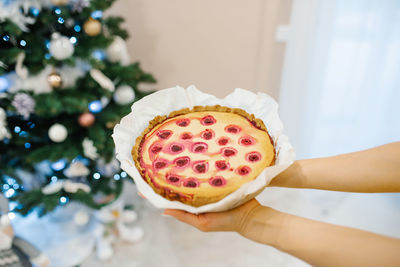 Baked cherry pie in hands on the background of the christmas tree person