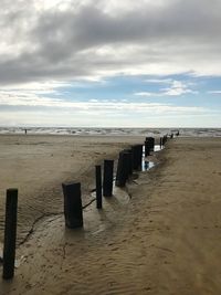 Wooden posts on beach against sky