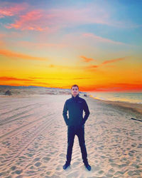 Full length portrait of man standing on beach during sunset