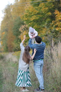 Rear view of friends standing against plants