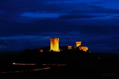 Low angle view of illuminated building against cloudy sky