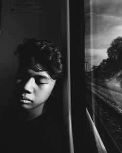 Close-up of teenage boy napping by window in train