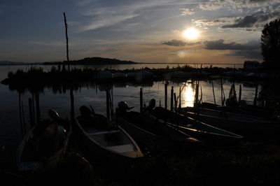 Silhouette sailboats moored in lake against sky during sunset