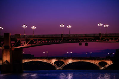 Bridge over river against sky at night