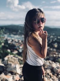 Girl wearing sunglasses standing against sky