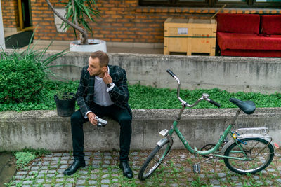 Man looking at bicycle against plants