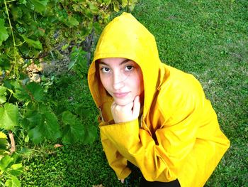 Portrait of woman in raincoat by plants on field