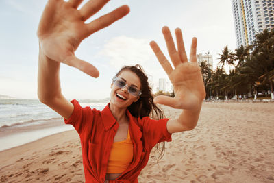 Young woman with arms raised at beach