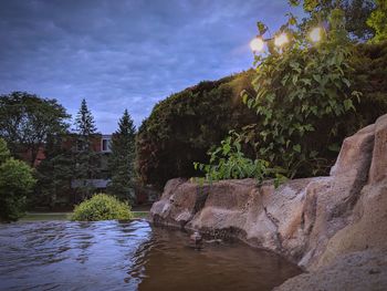 Rocks by river against sky