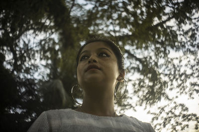 Low angle view of woman looking away against trees