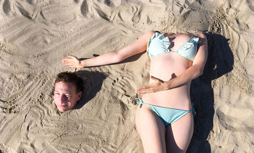 High angle view of friends relaxing on sand at beach